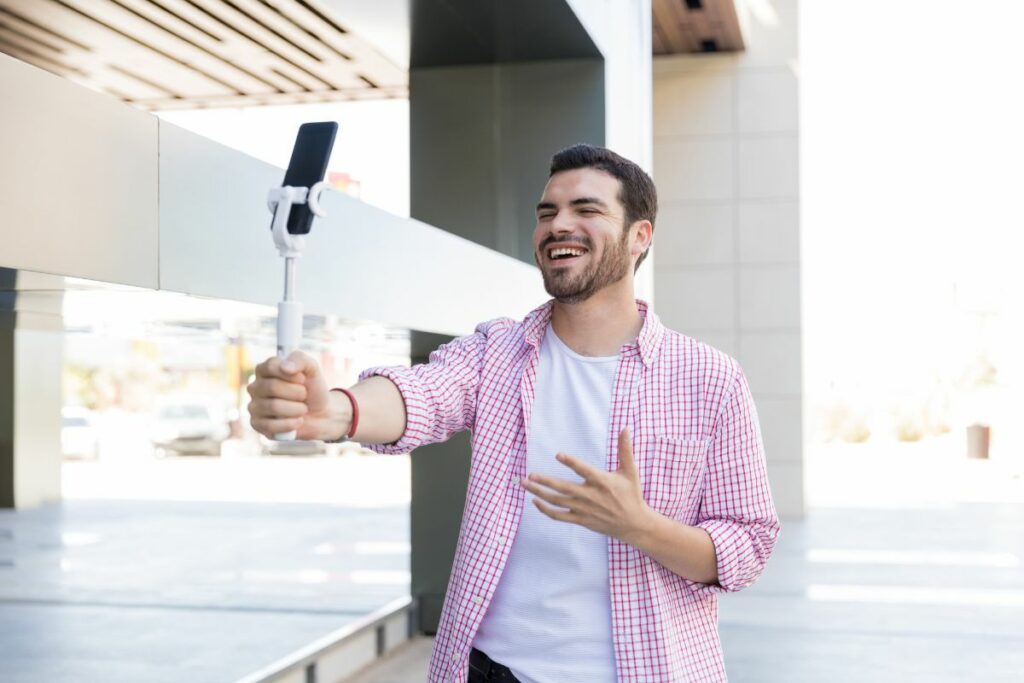 Un creador de contenido se graba mientras habla al celular. Foto: Freepik