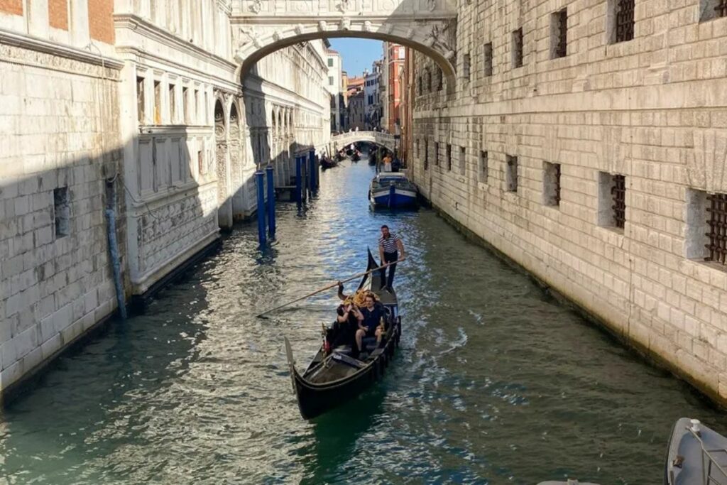 Una pareja disfruta de un viaje en góndola por un canal de Venecia.