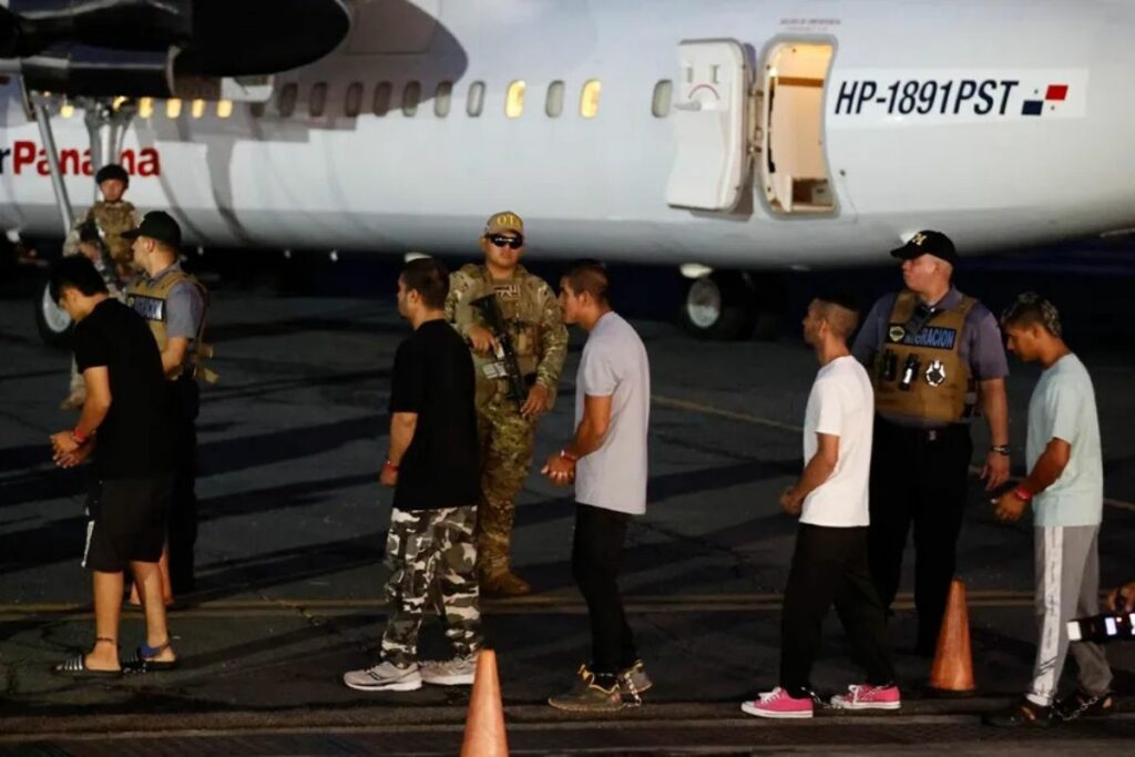 Migrantes caminan frente a un avión tras ser deportados de los Estados Unidos.