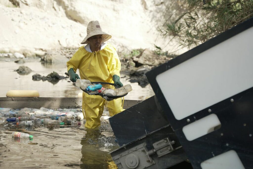 Fotografía cedida por Ichthion de un operador extrayendo residuos y desechos sólidos del río San Pedro, en Quito.