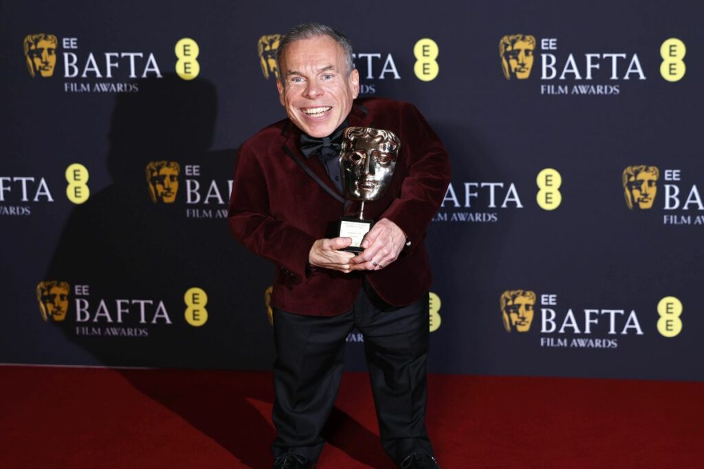 El actor Warwick Davis posa con su BAFTA honorífico. 