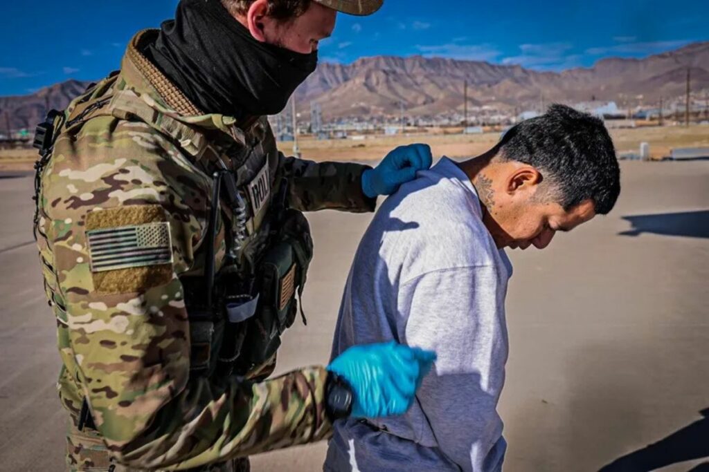 Fotografía cedida por el Departamento de Seguridad Nacional (DHS) donde aparece un agente guiando a un migrante venezolano hacia un avión militar par ser transportado a Guantánamo en Cuba.