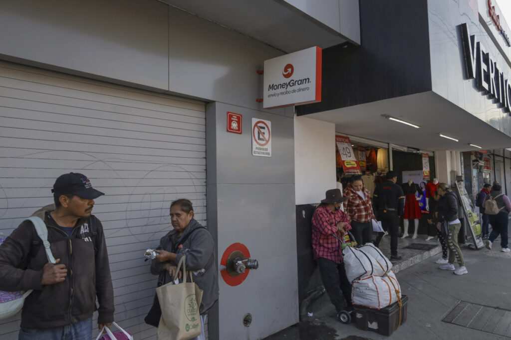 Personas esperan frente a un establecimiento de envío de dinero este lunes, en Tijuana (México).