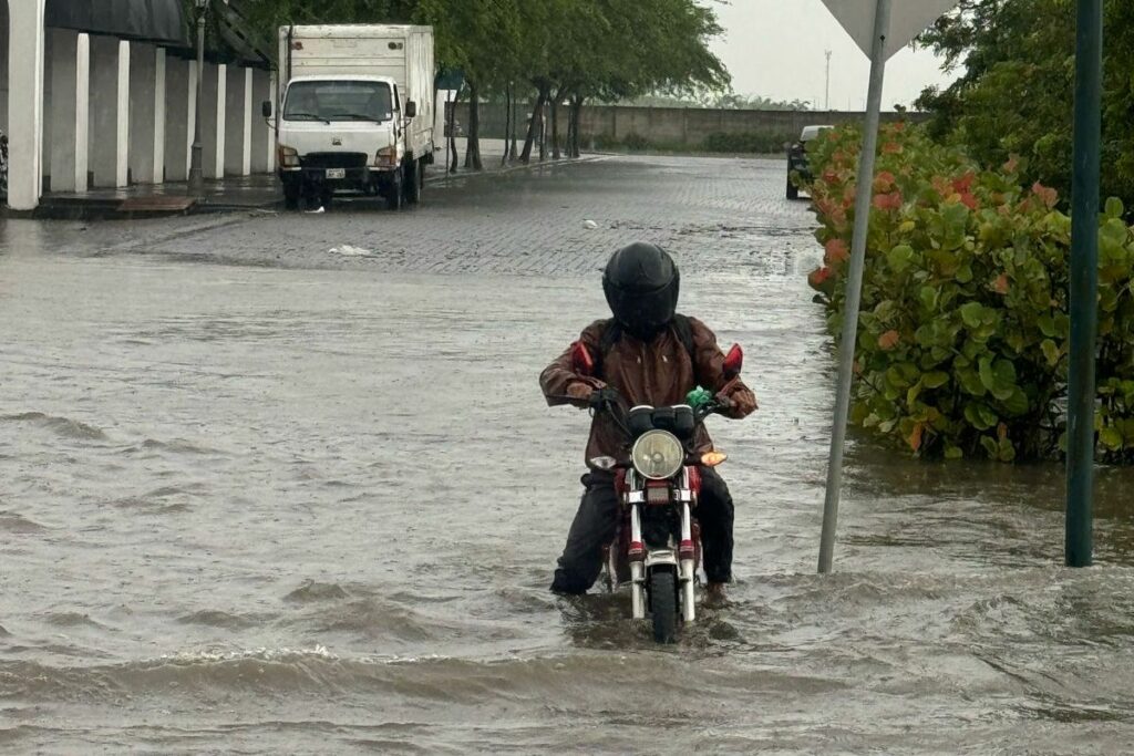 Un motociclista en una zona de Samborondón en medio del agua.