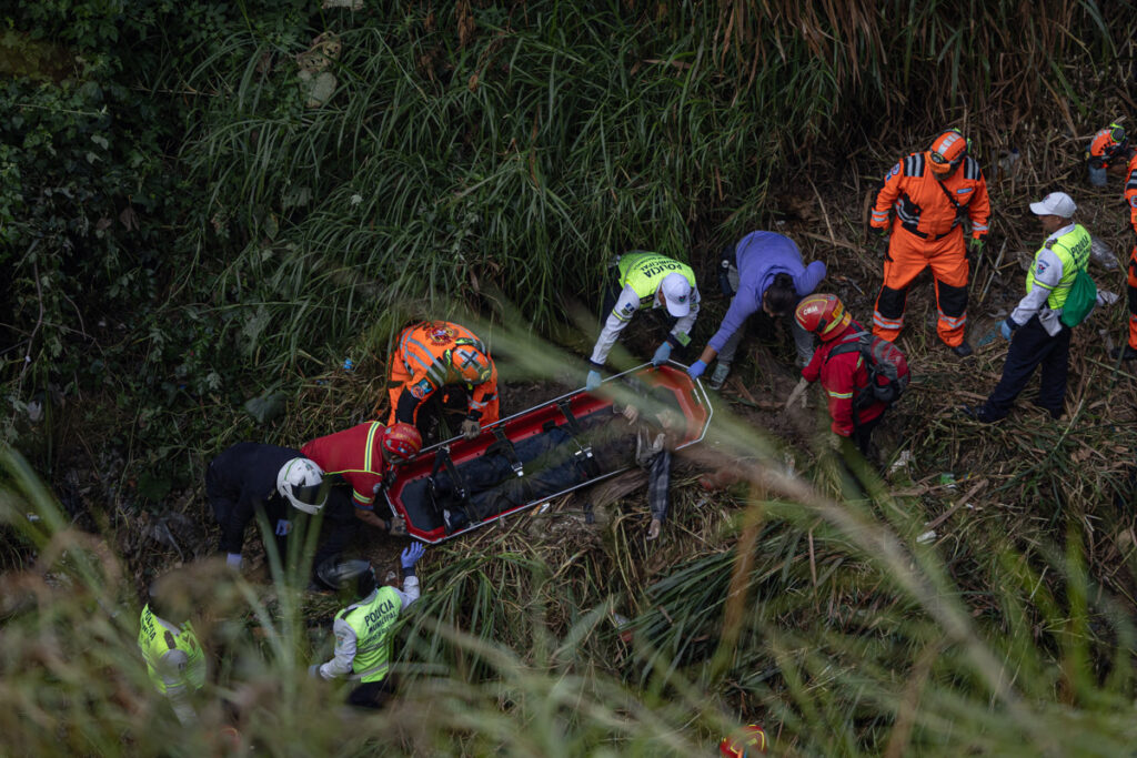 Integrantes de cuerpos de socorro de Guatemala recuperan el cuerpo de una de las 51 víctimas mortales del accidente de un autobús en Ciudad de Guatemala.