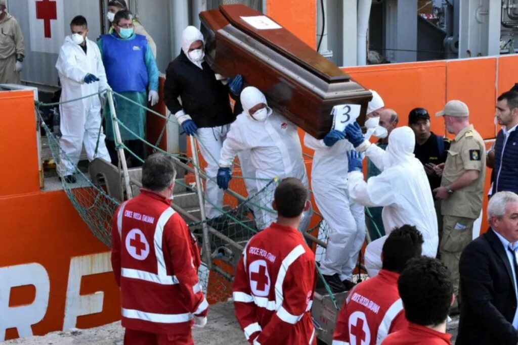 Varios operarios bajan a tierra en el puerto italiano de Palermo el ataúd de un migrante muerto, en una imagen de archivo.