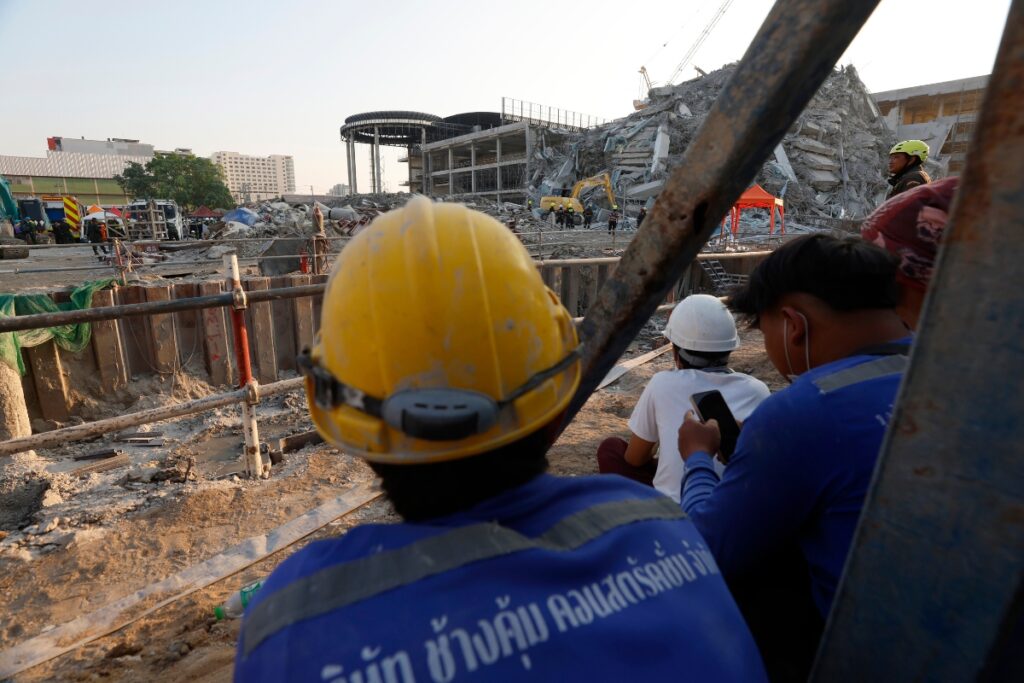 Trabajadores de la construcción esperan a compañeros que se cree están atrapados dentro de un edificio colapsado tras un terremoto.