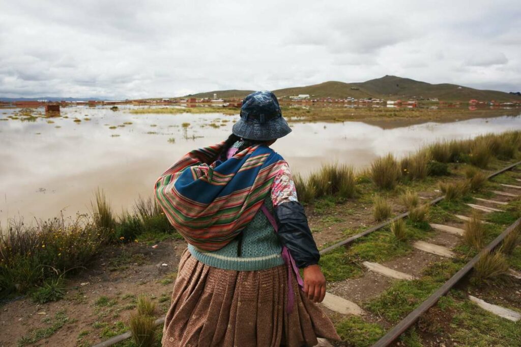 Una mujer aimara camina por el borde de un río tras fuertes lluvias este viernes, en Viacha (Bolivia).