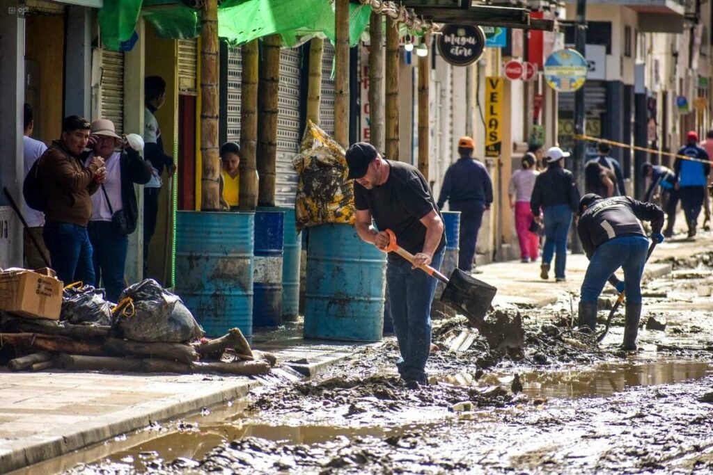 Ciudadanos limpian el lodo que dejaron las fuertes lluvias en las calles de Loja