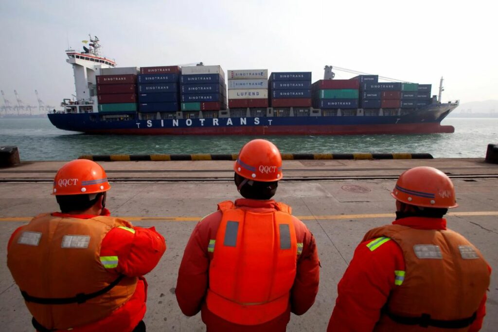 Trabajadores del puerto de Qingdao observan pasar a un barco contenedor de la compañía china Sinotrans Shipping Ltd., en una foto de archivo.