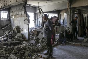 Palestinos desplazados internos inspeccionan los daños en el sitio de una clínica de la ONU tras un ataque aéreo israelí.