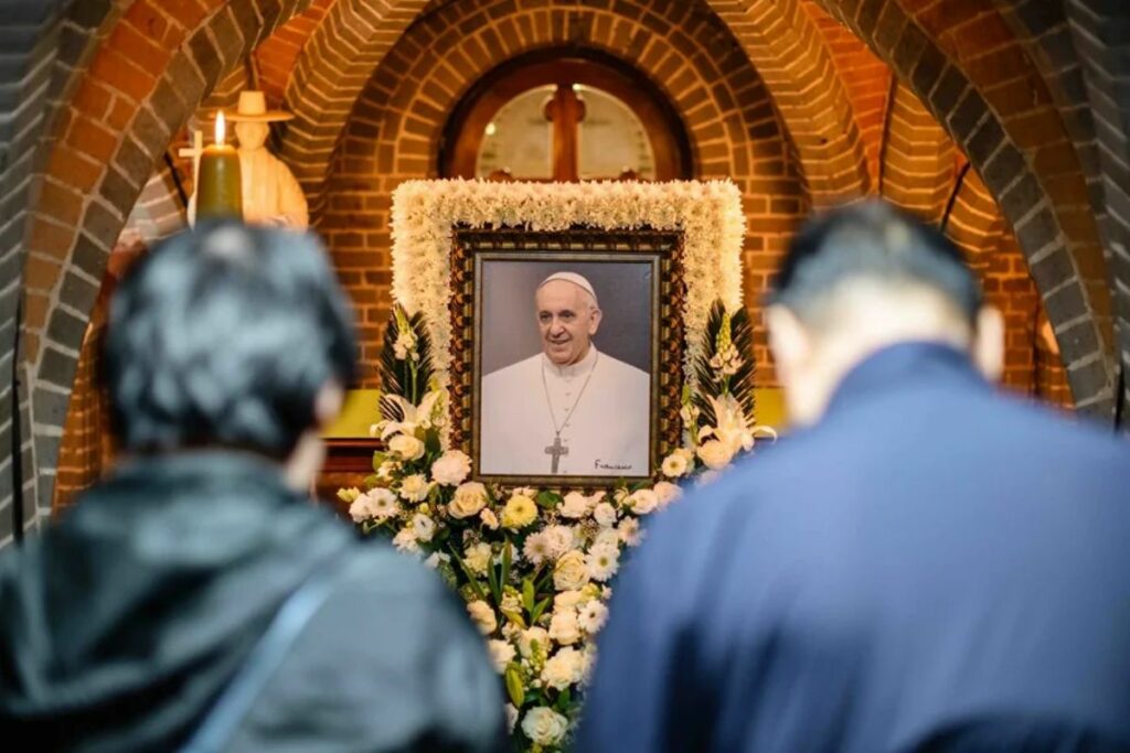 Un grupo de personas reza ante una imagen del papa Francisco, en la catedral de Seúl. Foto: EFE