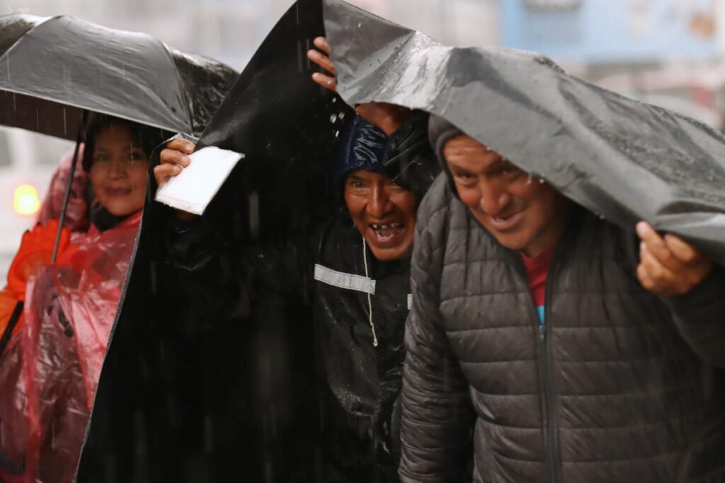 Personas se cubren con un plástico ante las lluvias en Quito