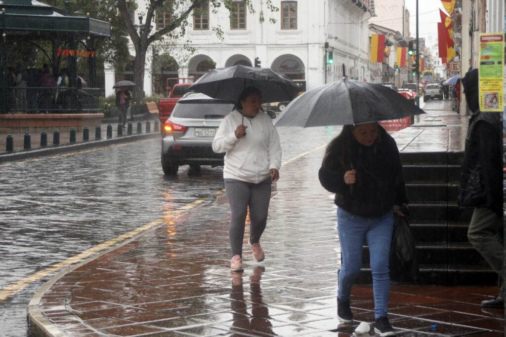 Personas caminan en las calles de Cuenca con lluvia.