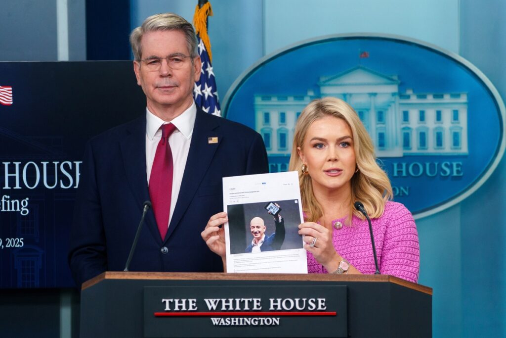La secretaria de prensa de la Casa Blanca, Karoline Leavitt (C), sostiene una fotografía del fundador de Amazon, Jeff Bezos.
