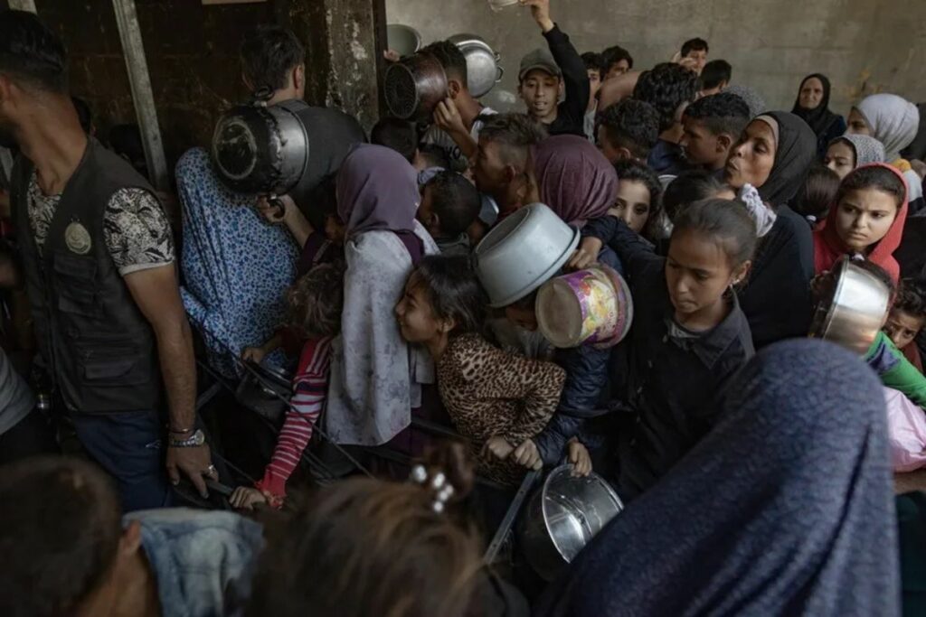 Decenas de palestinos se amontonan frente al Comedor Social Sokar, en la ciudad de Gaza, para conseguir raciones de comida.