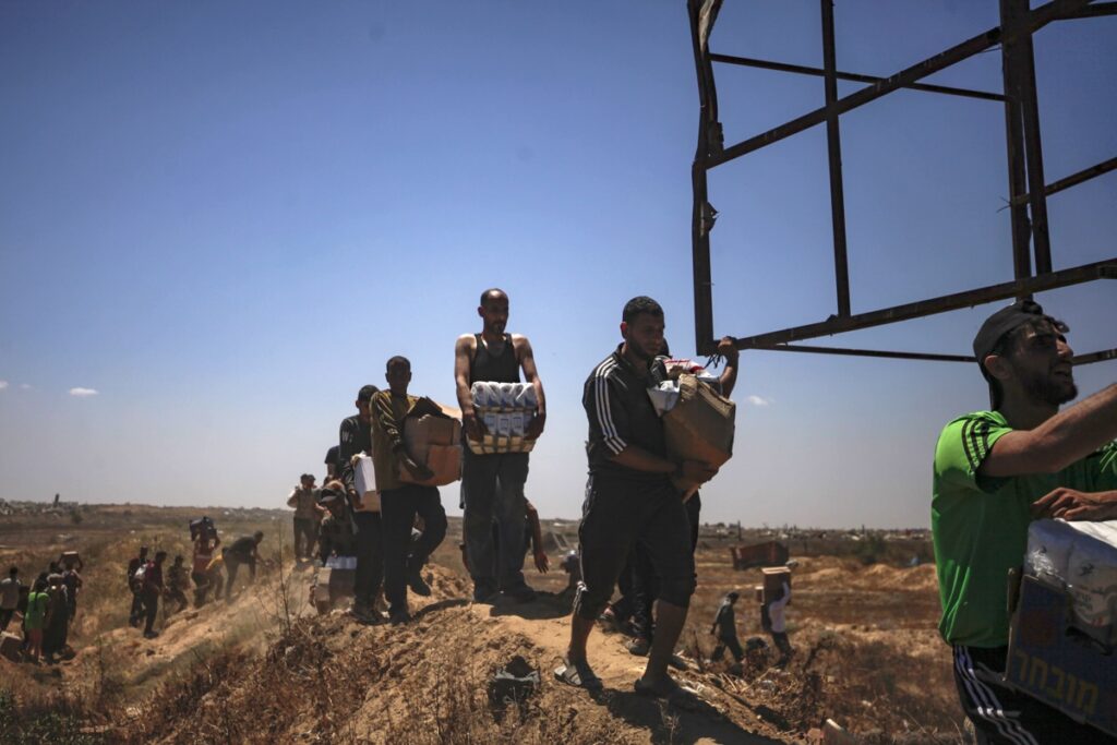 Palestinos transportan suministros de ayuda recibidos de la Fundación Humanitaria de Gaza, respaldada por Estados Unidos, a través de una zona conocida como el Corredor Netzarim, en el centro de la Franja de Gaza, el 29 de mayo de 2025.