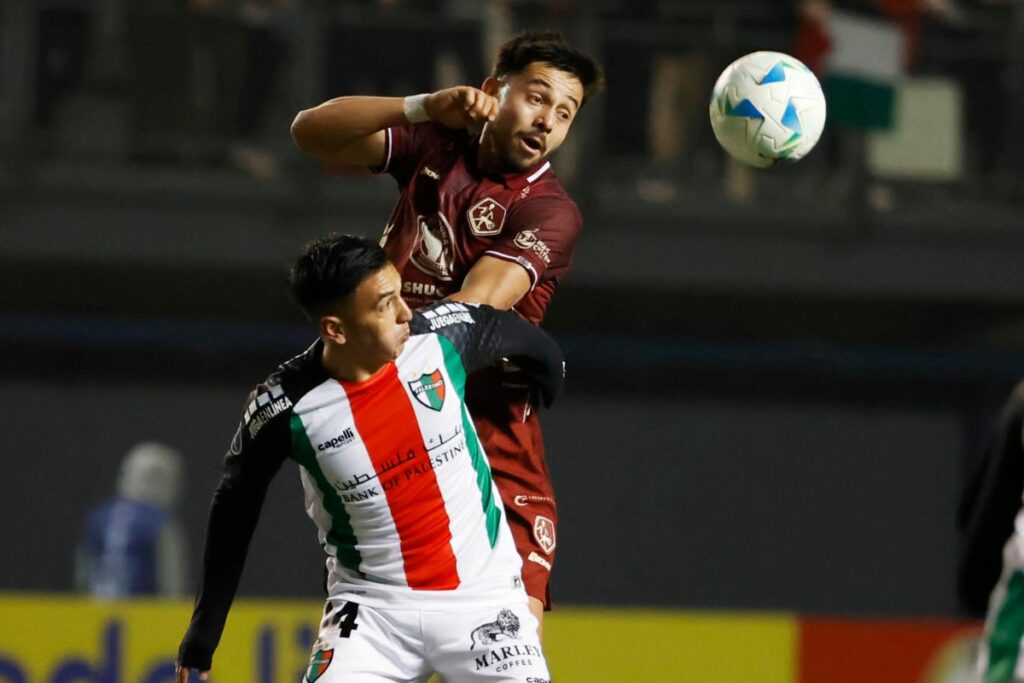 Joe Abrigo (abajo) de Palestino disputa el balón con Esteban Dávila de Mushuc Runa en un partido de la fase de grupos de la Copa Sudamericana en el estadio Bicentenario de La Florida en Santiago.