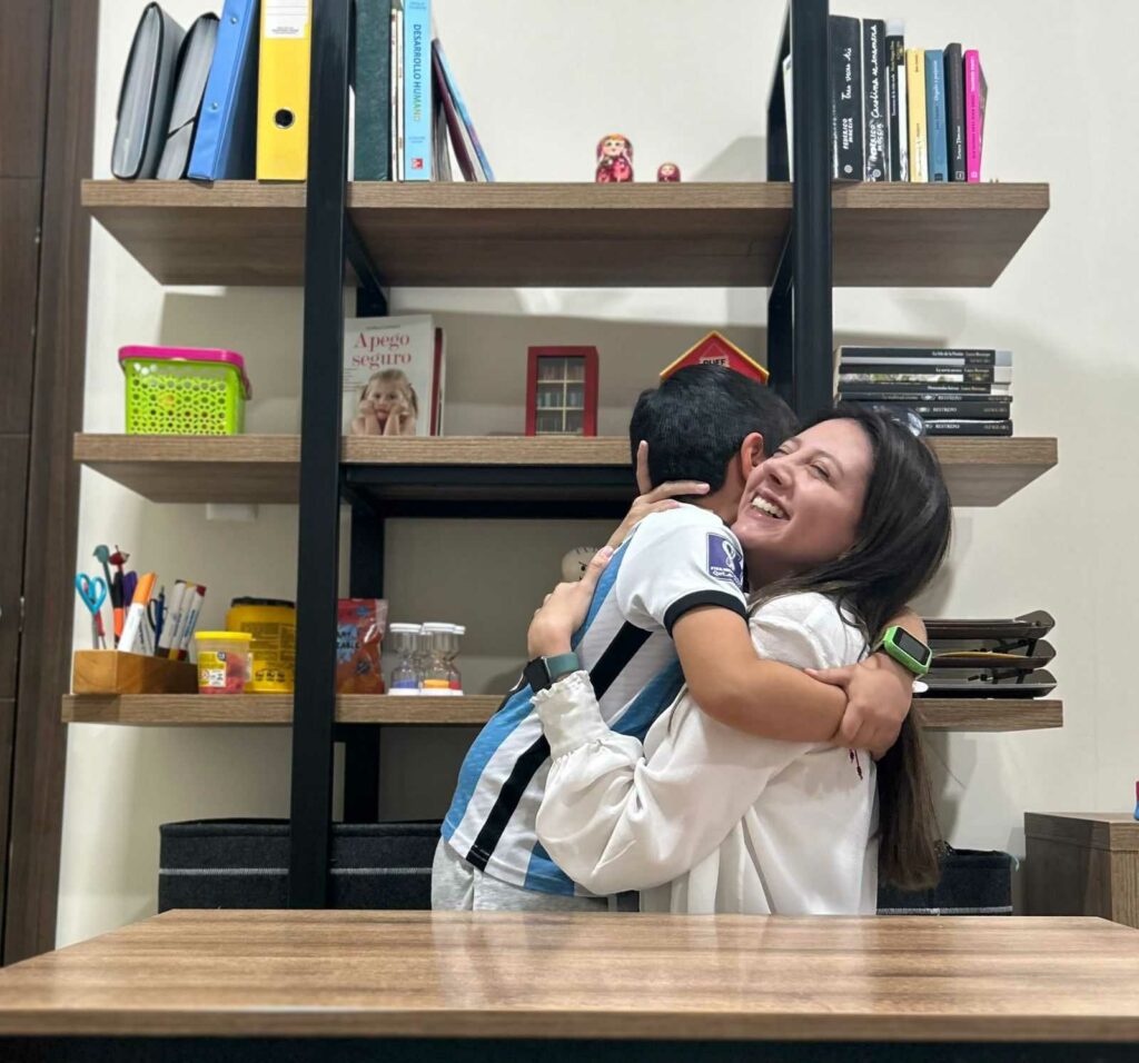 La psicóloga infantojuvenil, Doménica Rodríguez, recibe un abrazo de un niño que recibe terapias.  