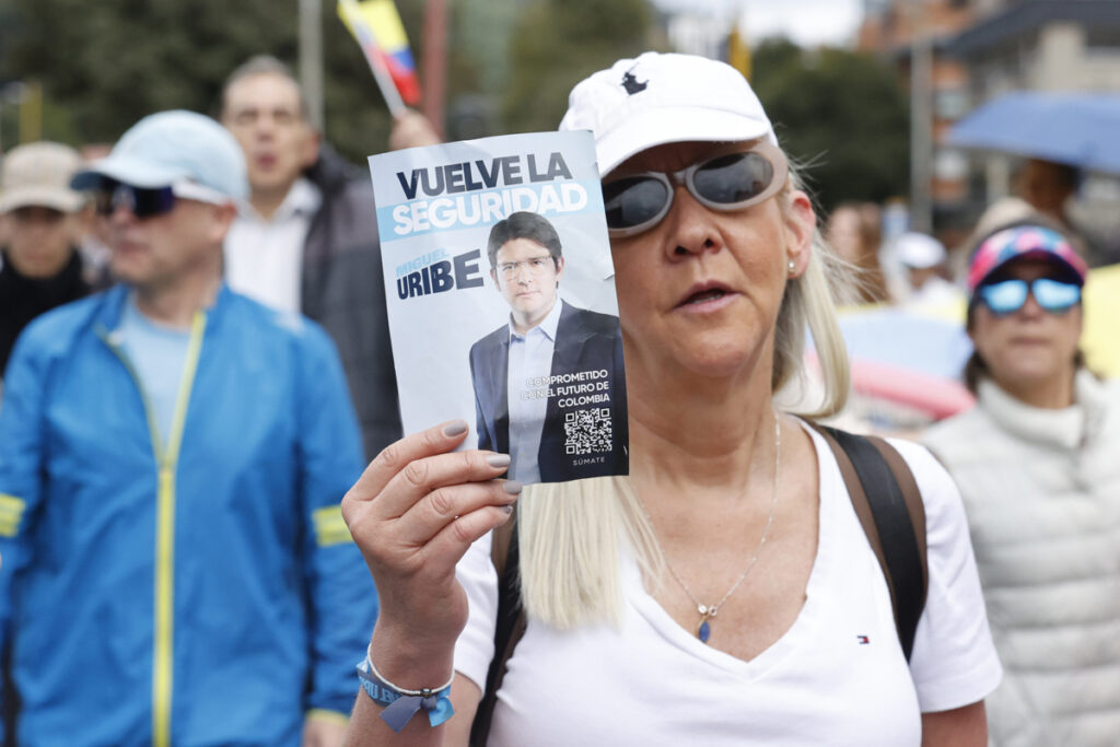 Una mujer sostiene un cartel durante una Caminata por la paz y en apoyo al senador Miguel Uribe Turbay, quien sufrió un grave atentado en Bogotá.