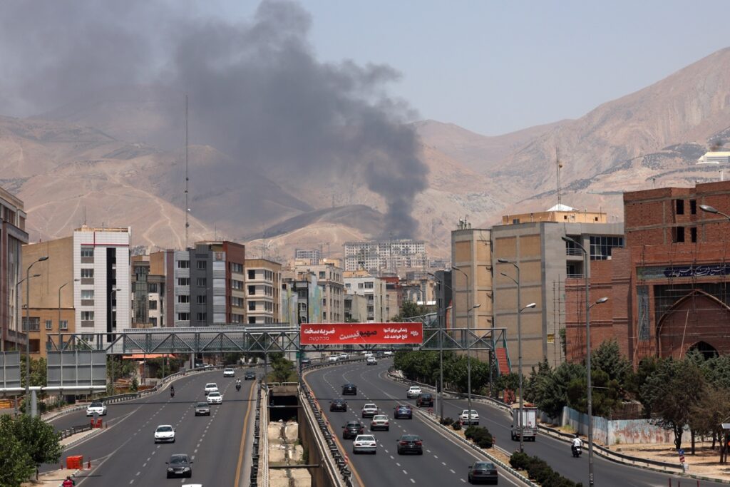 Vehículos circulan por una autopista mientras se eleva humo al fondo desde una refinería de petróleo, al noroeste de Teherán, Irán. Foto: EFE