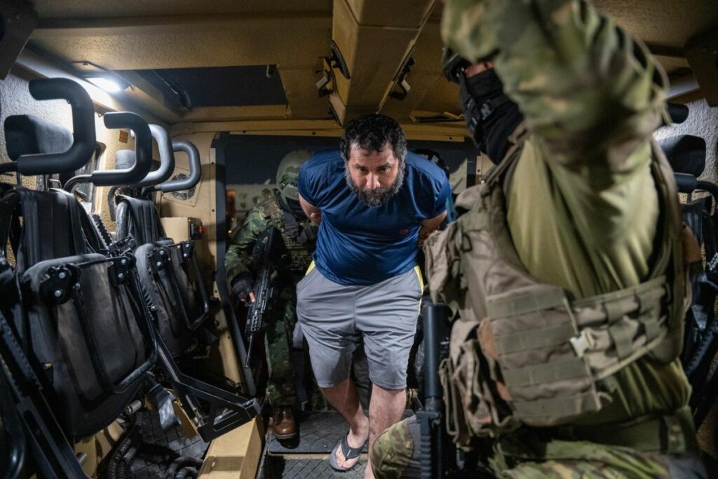 José Adolfo Macías Villamar, alias 'Fito', es custodiado a su llegada a la Base Aérea de Guayaquil. Foto EFE