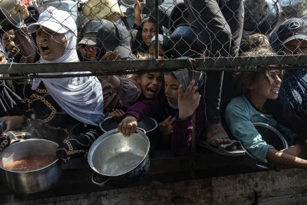 Palestinos tratan de recibir raciones limitadas de comida, en Khan Younis, al sur de la Franja de Gaza. Foto: EFE