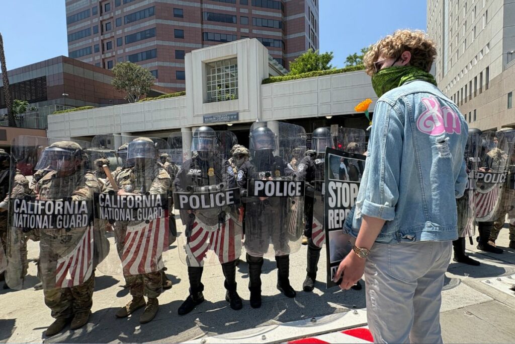 Un manifestante exhibe un cartel a miembros de la Guardia Nacional y Policía de Los Ángeles en el exterior de un centro de detención. FOTO: María José Aguilar / EL COMERCIO.