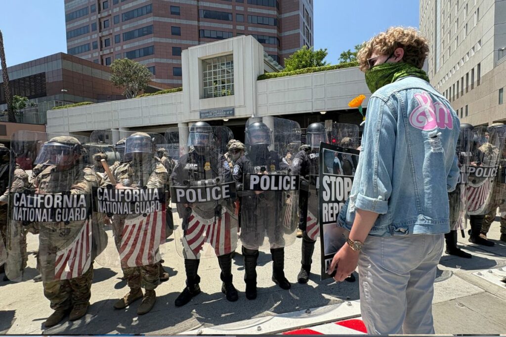 Un manifestante exhibe un cartel frente a la Guardia Nacional y Policía a las afueras de un centro de detención federal en las protestas de Los Ángeles. FOTO: María José Aguilar, EL COMERCIO.