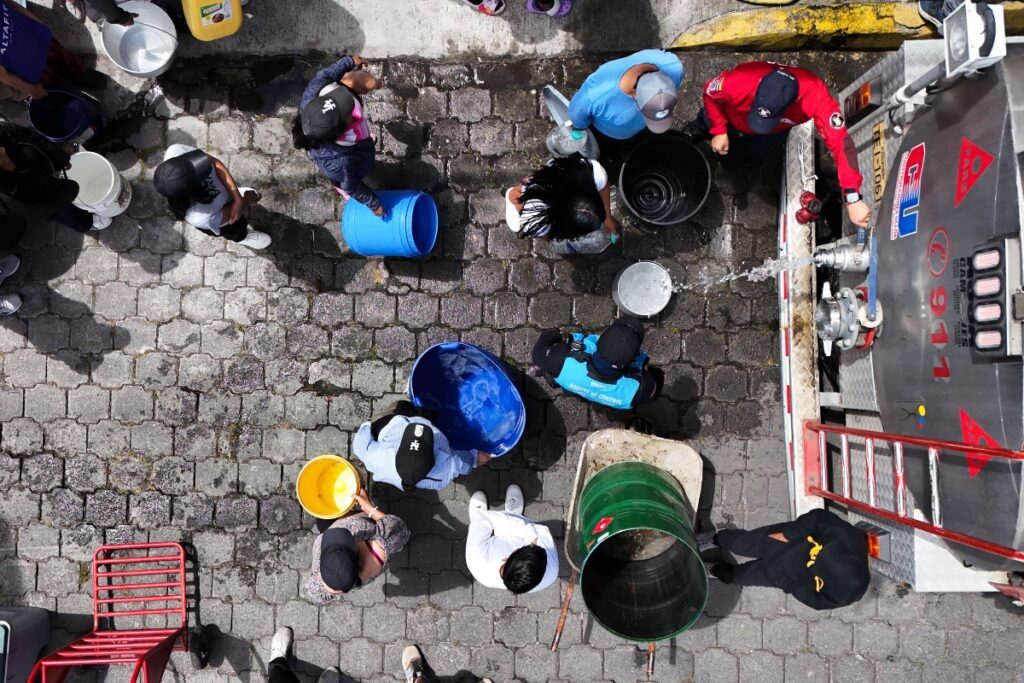 Moradores del sur de Quito recolectan agua de un tanquero.