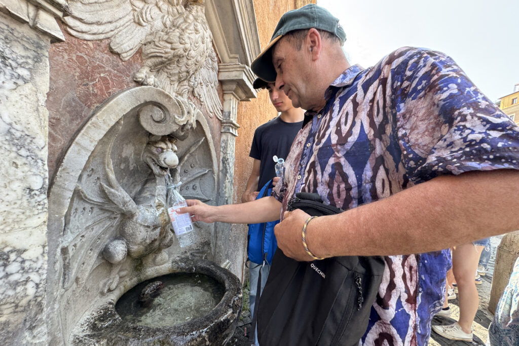 Un hombre se refresca en una fuente en Italia.