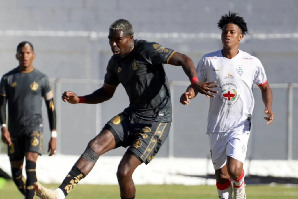 Michael Carcelén (i) de Aucas controla el balón ante la mirada de un jugador de Ecuagenera.