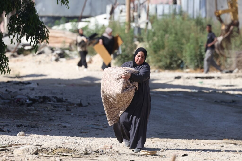 Un palestino desplazado que lleva sus pertenencias camina por una carretera durante una operación militar israelí en el campo de refugiados de Tulkarem.