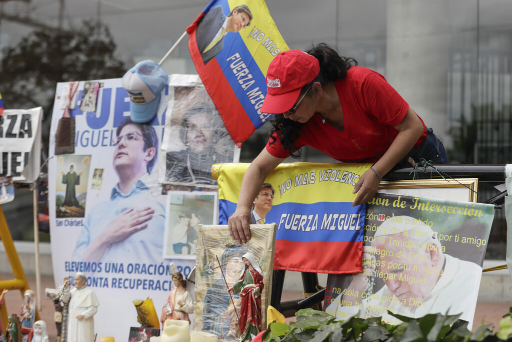 Una persona arregla un altar improvisado frente a la Fundación Santa Fe, lugar donde permanece hospitalizado el senador colombiano Miguel Uribe.