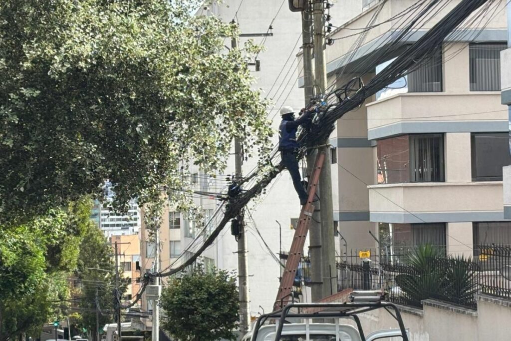 Una escena de todos los días en Quito: trabajdores de operadores privados de telecomunicaciones que atan más cables a los postes del alumbrado público.