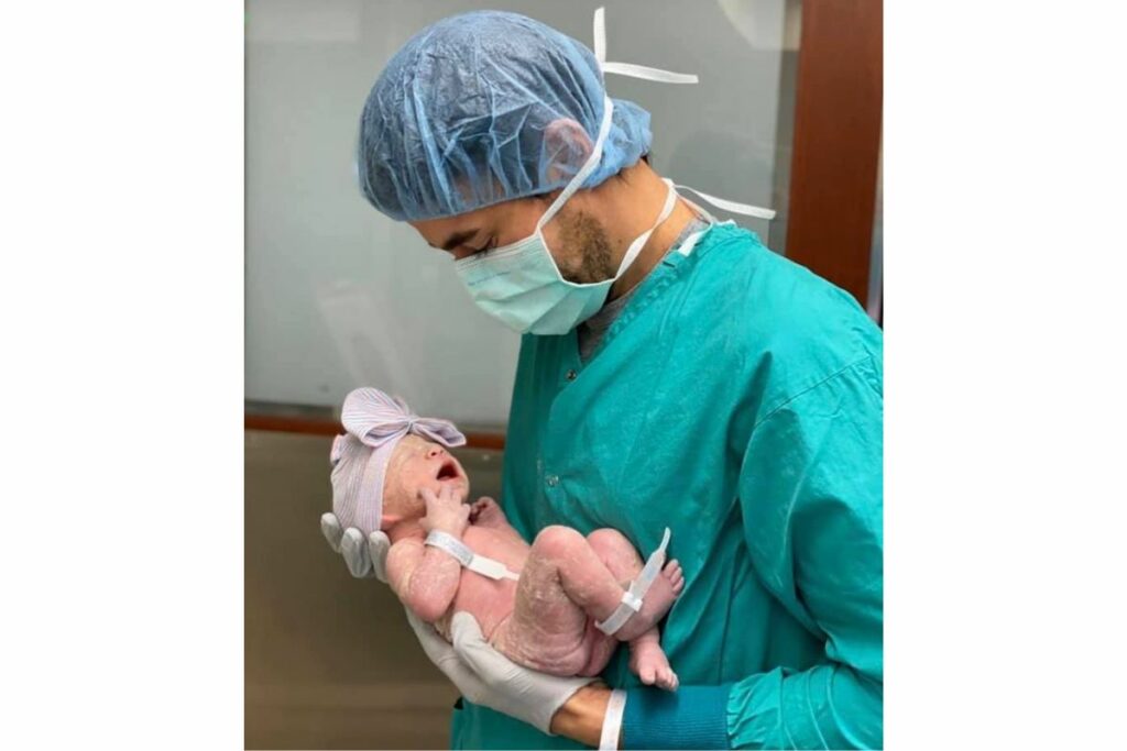 Enrique Iglesias sostiene a uno de sus hijos que acaba de nacer.