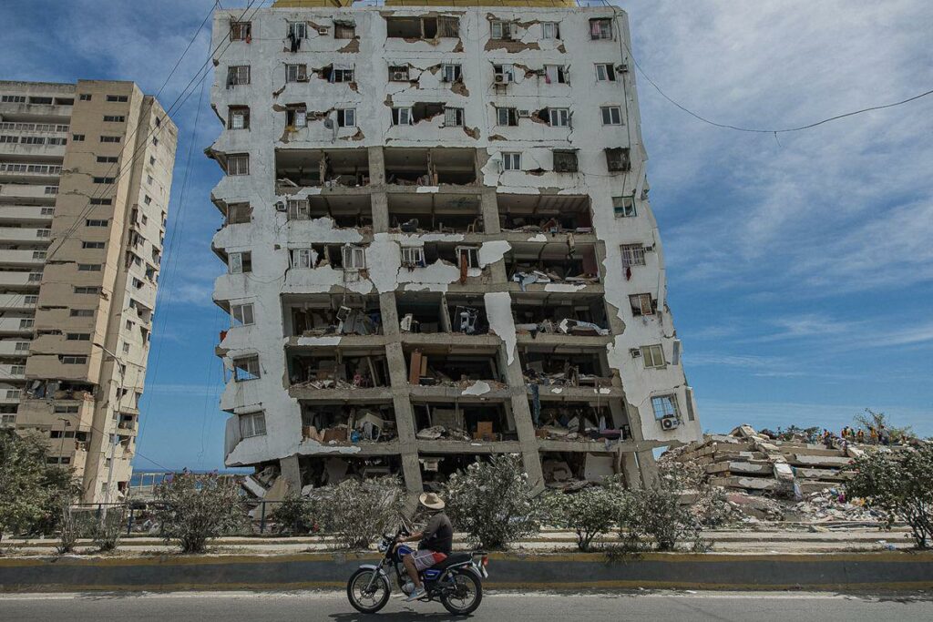 Una persona transita frente a un edificio destruido por los terremotos, este domingo, en Catia La Mar (Venezuela).