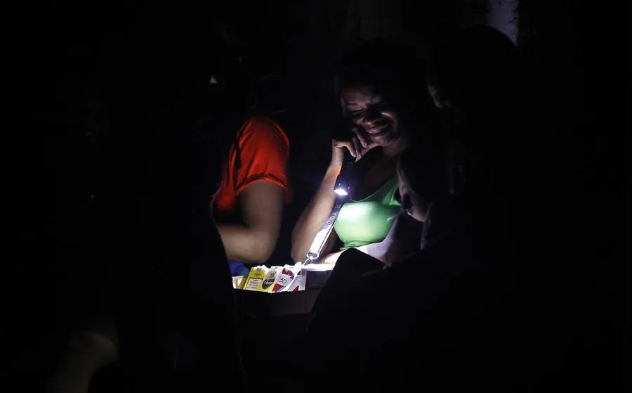 Una mujer ilumina con una linterna cigarros para venderlos durante un apagón, en La Habana (Cuba)