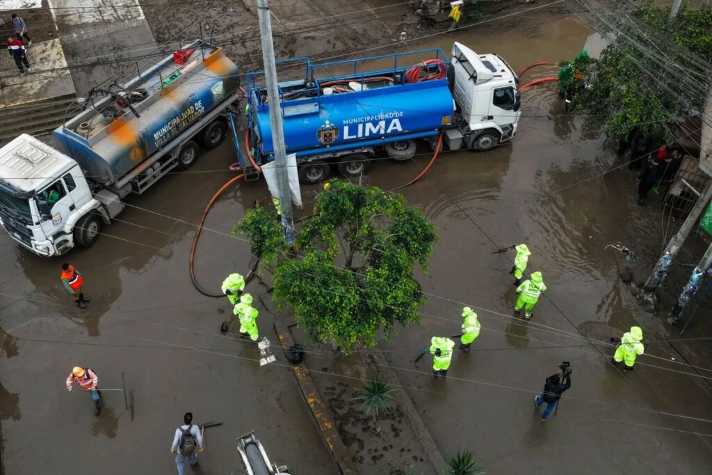 Fotografía cedida por Agencia Andina que muestra a funcionarios de la Municipalidad de Lima trabajando en una calle inundada.